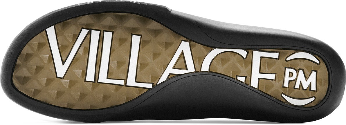 A close-up of a shoe sole featuring a textured tan and brown geometric pattern with the brand name 'VILLAGE PM' printed in bold white letters, bordered by a black rubber edge.