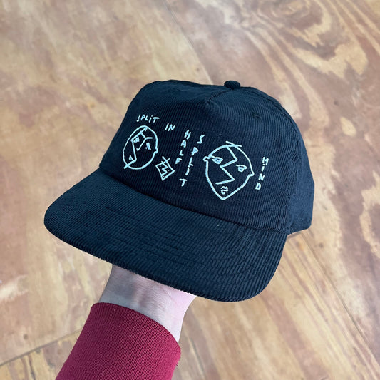 Black corduroy hat with a white graphic with faces.