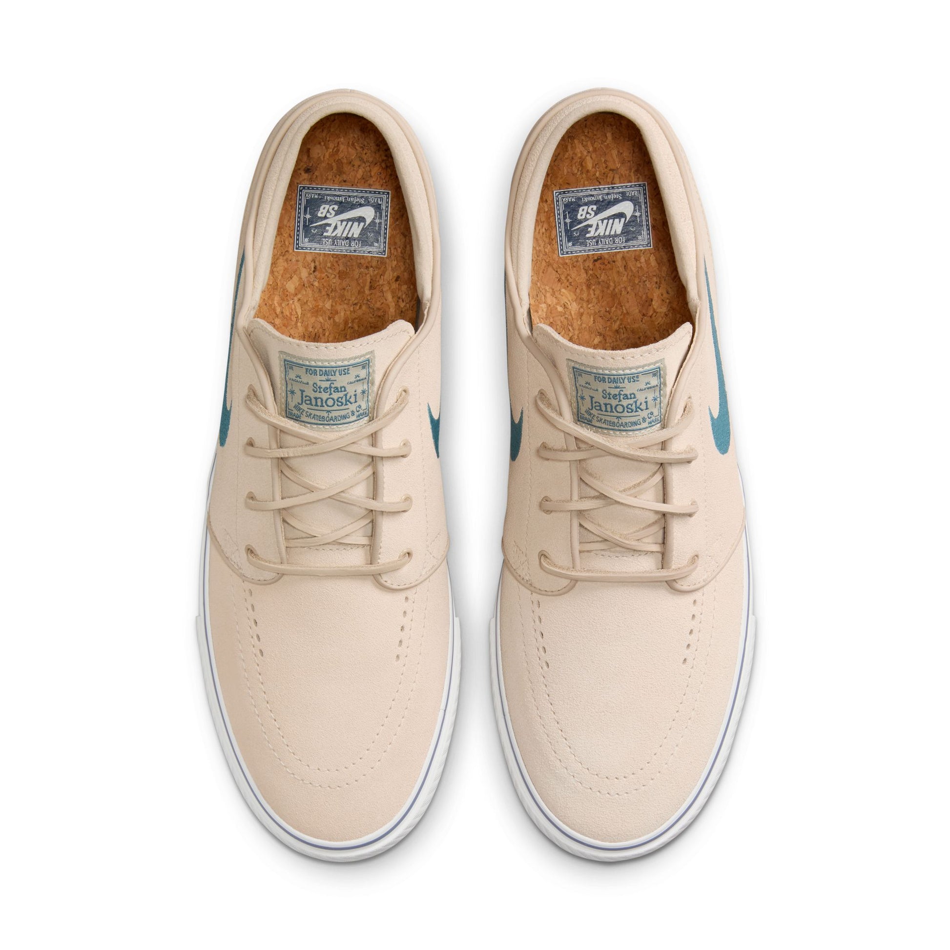 top view of cream colored low top suede skateboard shoe with white sole and light blue swoosh, cork soles visible