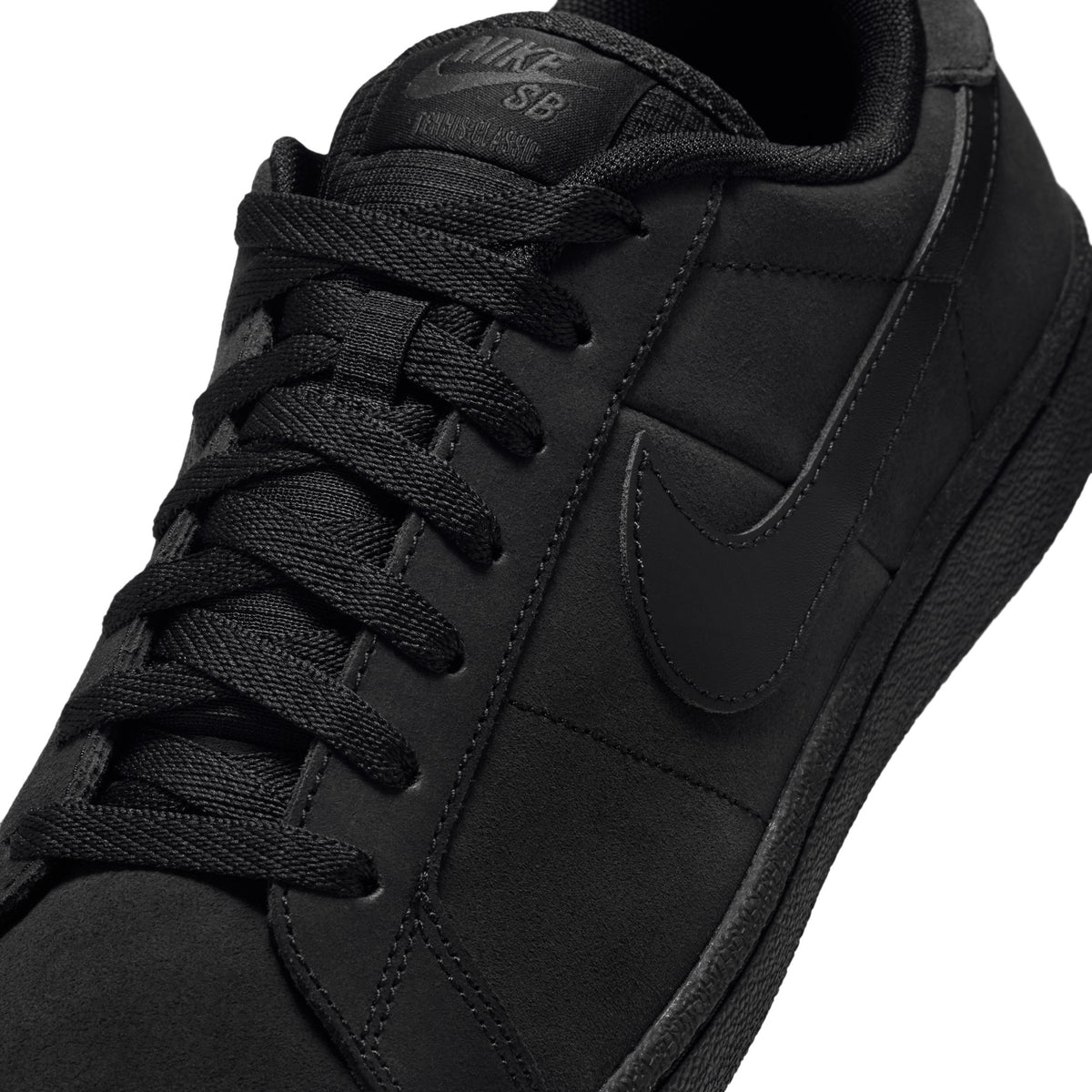 A close-up of a black Nike SB sneaker, showing the side profile with a tonal black Swoosh logo, black laces, and a black Nike SB tongue label on a white background.