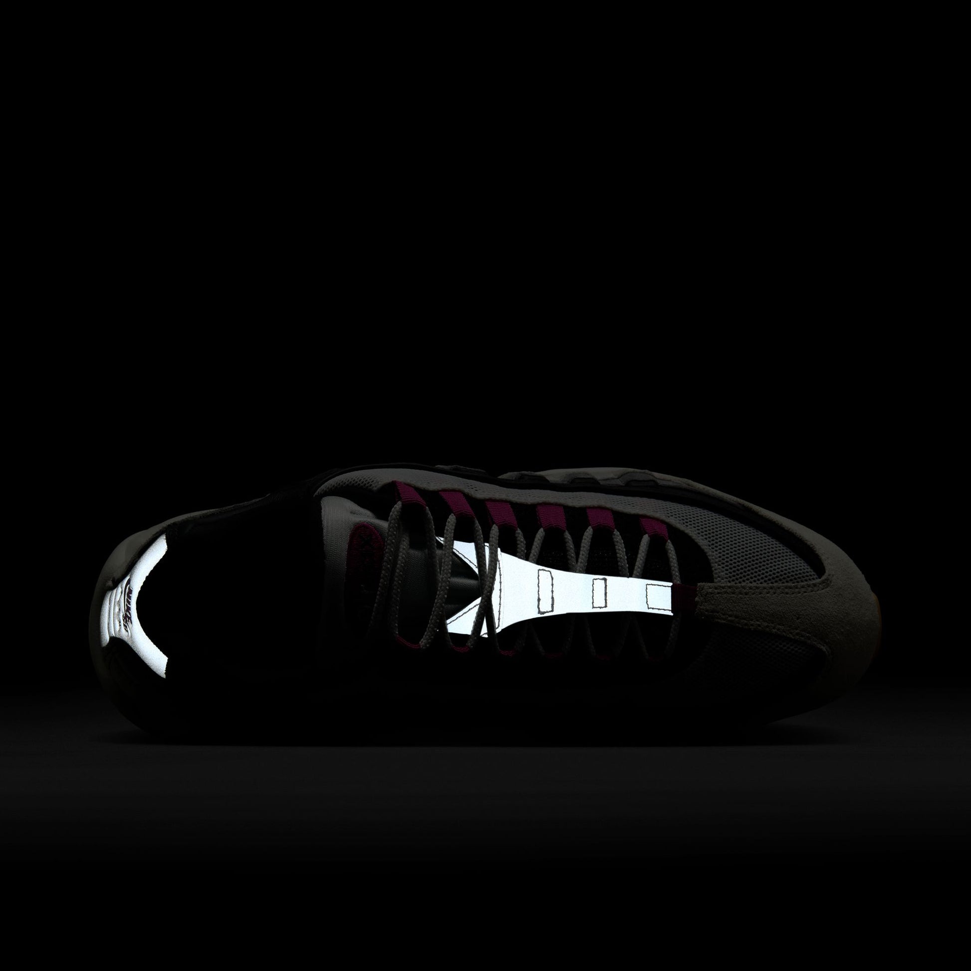 sneaker with reflective sole details visible on a black background