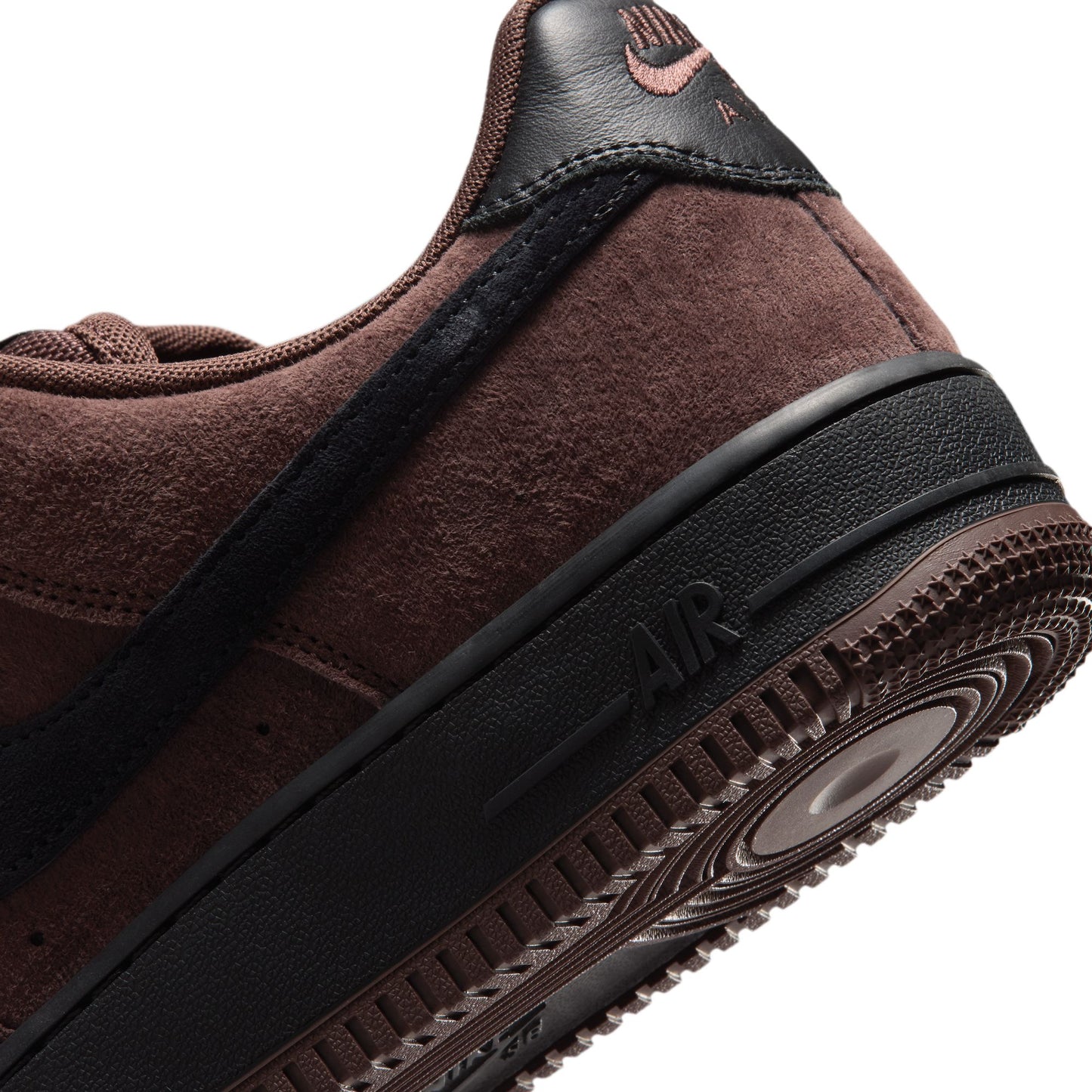 Close-up of a Nike Air Force 1 sneaker in dark brown suede and black, showing the heel, side profile, midsole, and outsole against a white background.