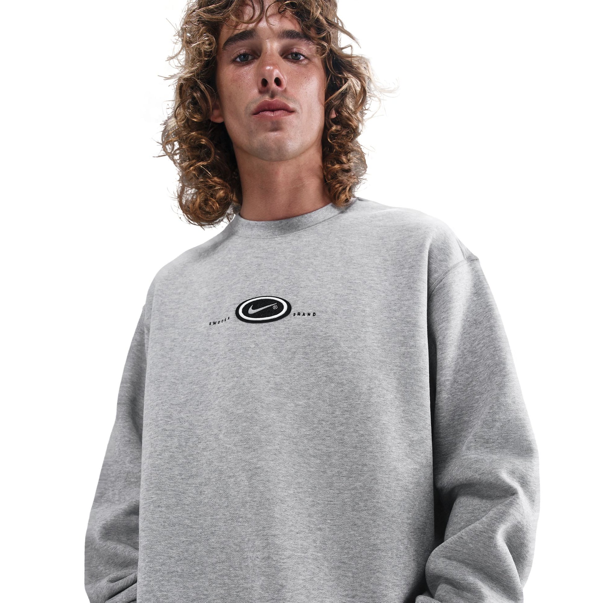 Person wearing a gray sweatshirt with a logo on a white background