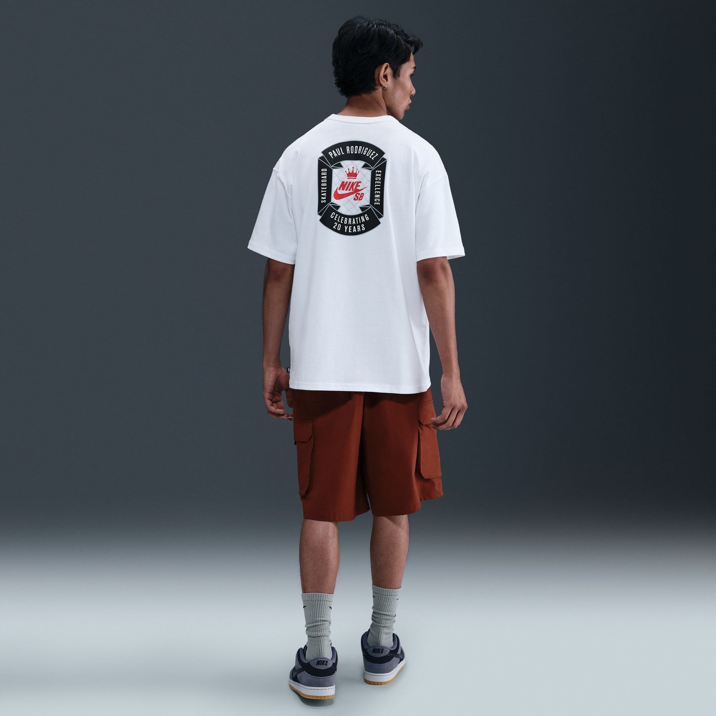 Person wearing a white t-shirt with a logo on the back against a gray background