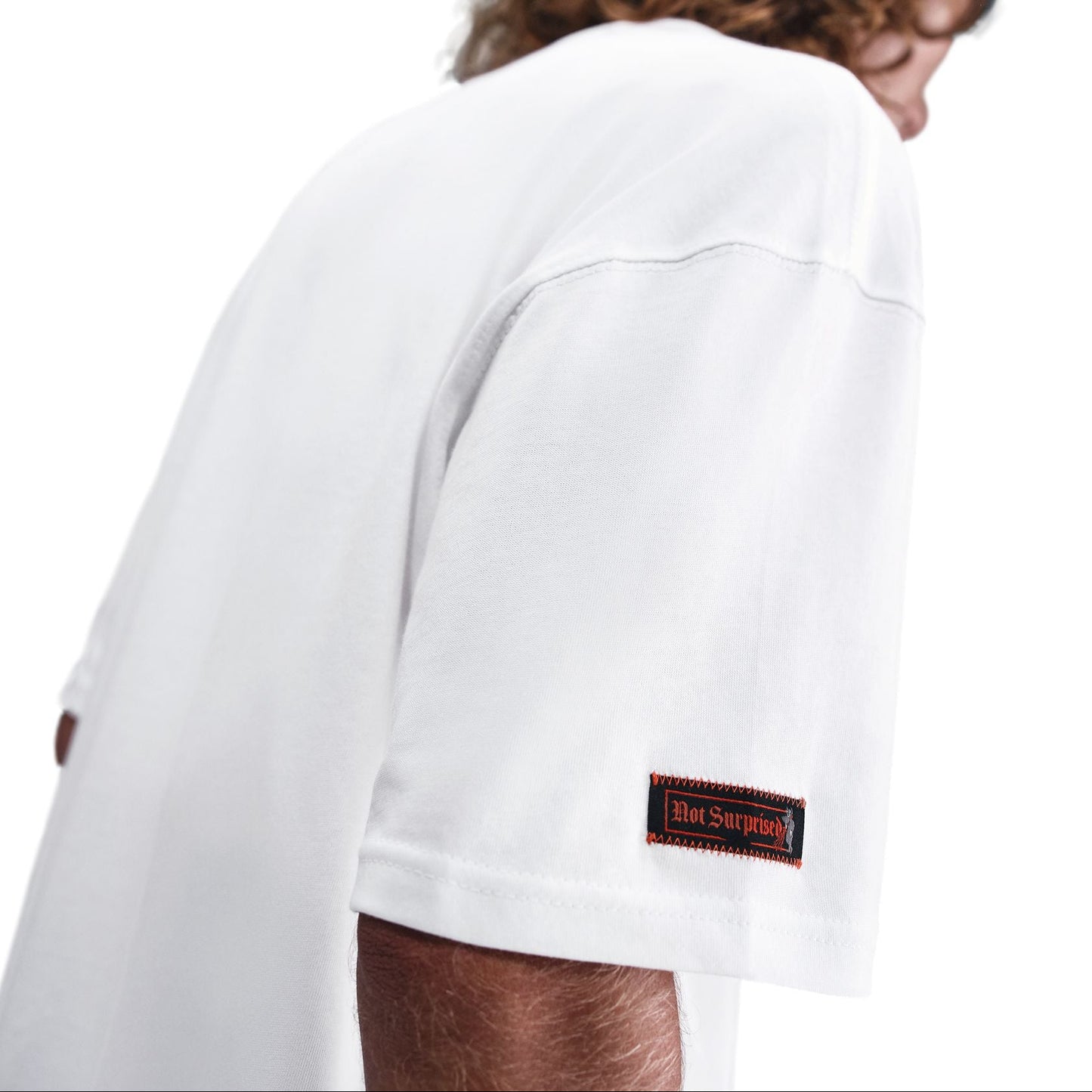 Person wearing a white t-shirt with a brand logo on the sleeve against a white background