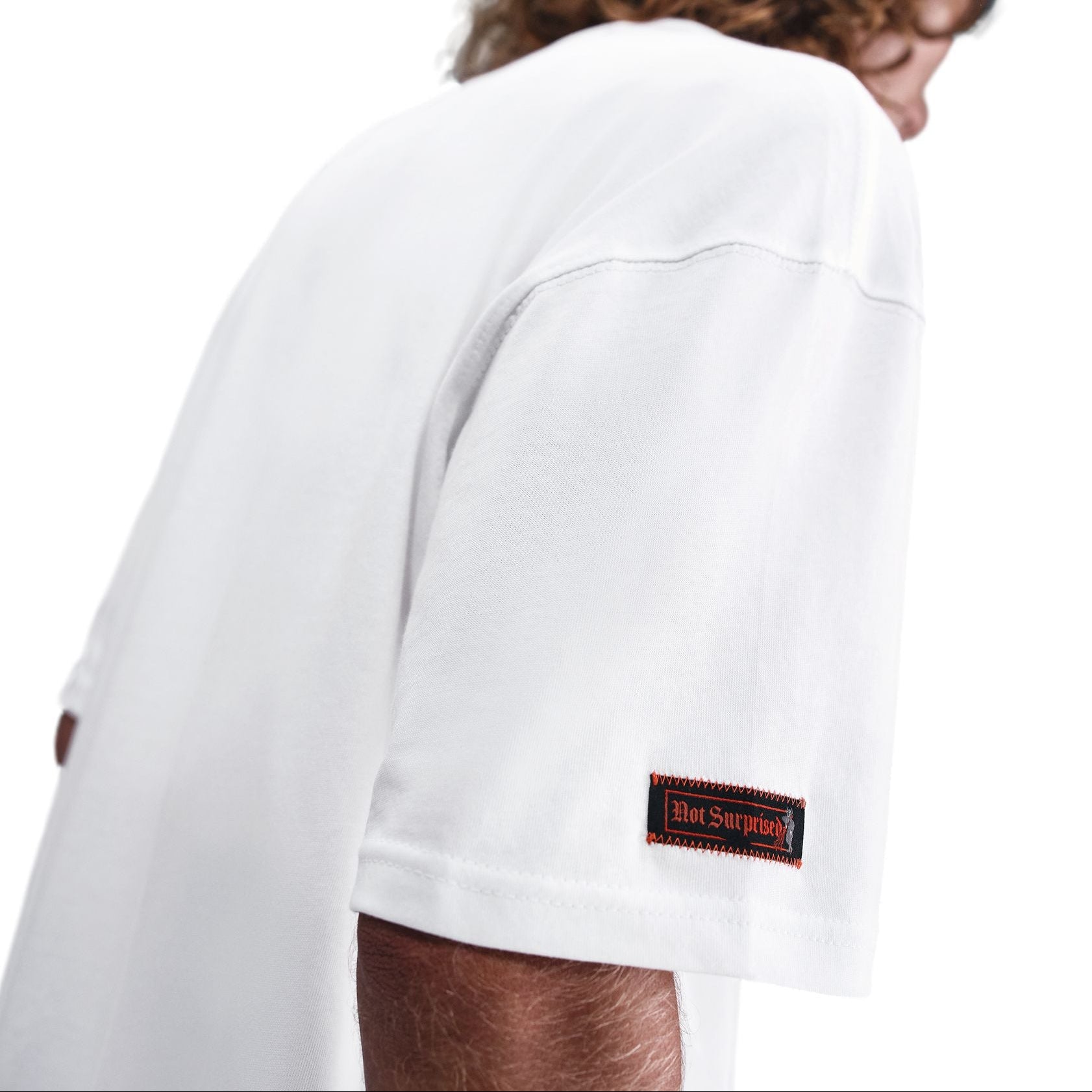 Person wearing a white t-shirt with a brand logo on the sleeve against a white background