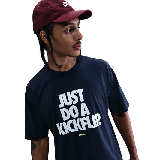 Person wearing a navy blue t-shirt with 'JUST DO A KICKFLIP?' text and a maroon cap.