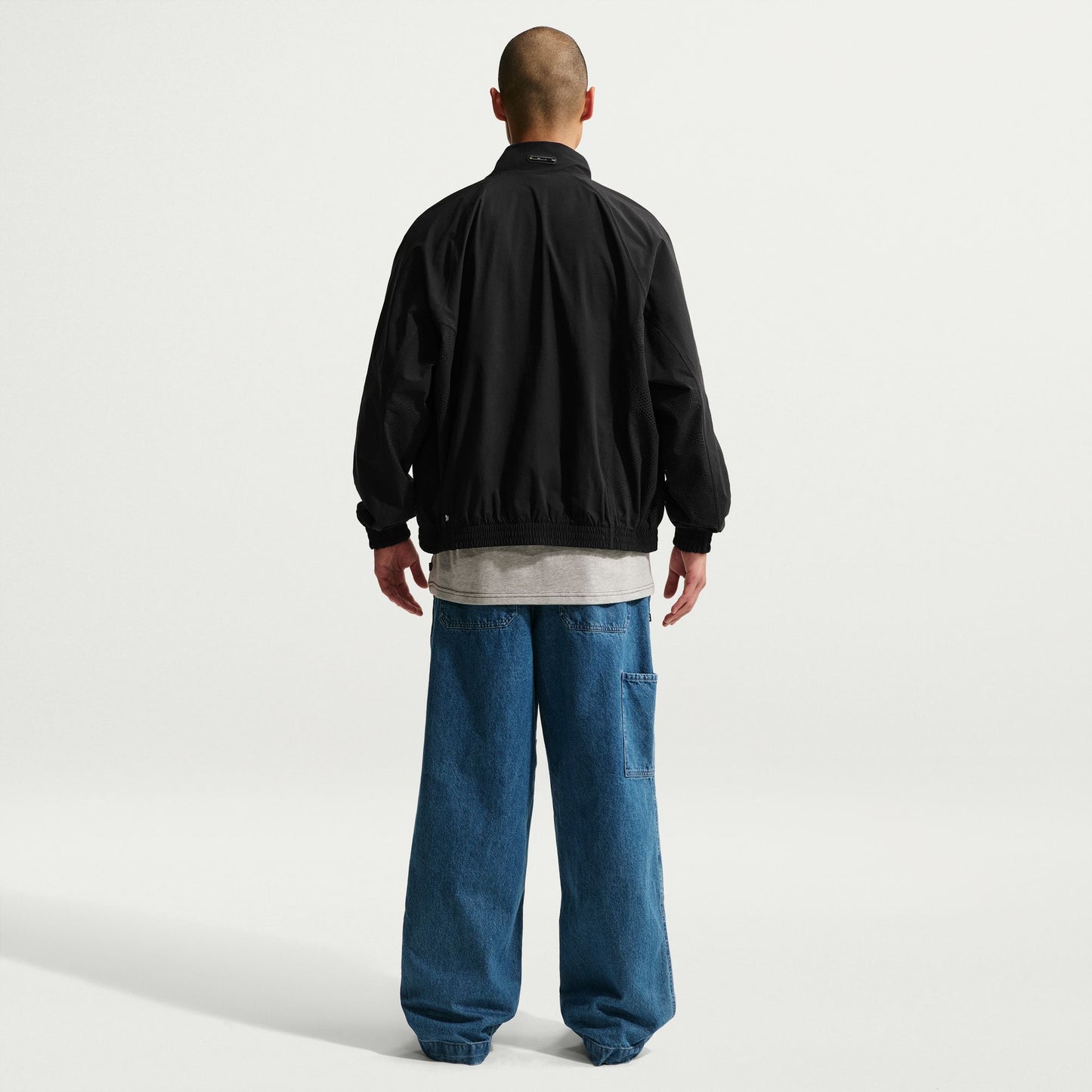 Person wearing a black jacket and blue jeans on a white background
