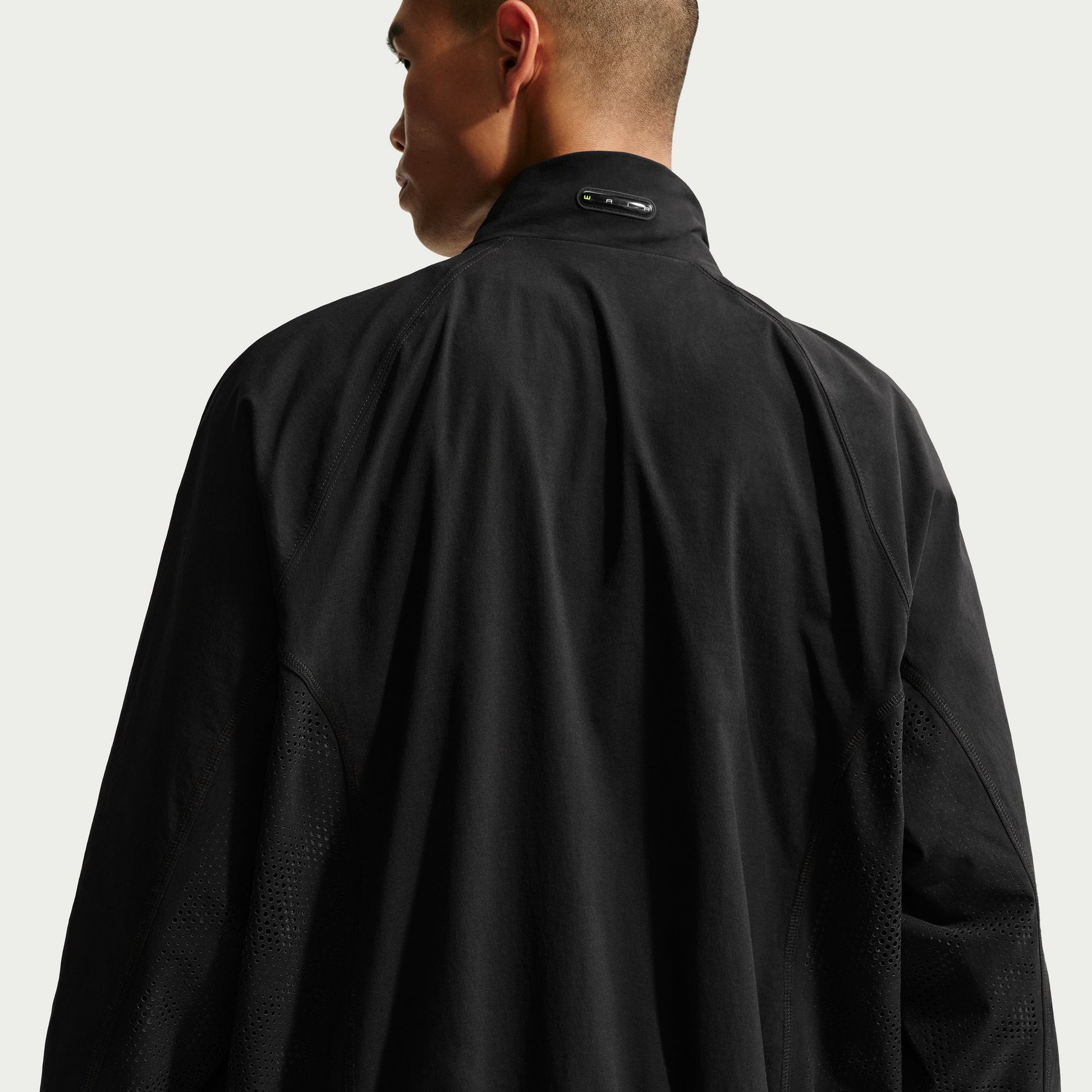 Person wearing a black jacket on a light gray background