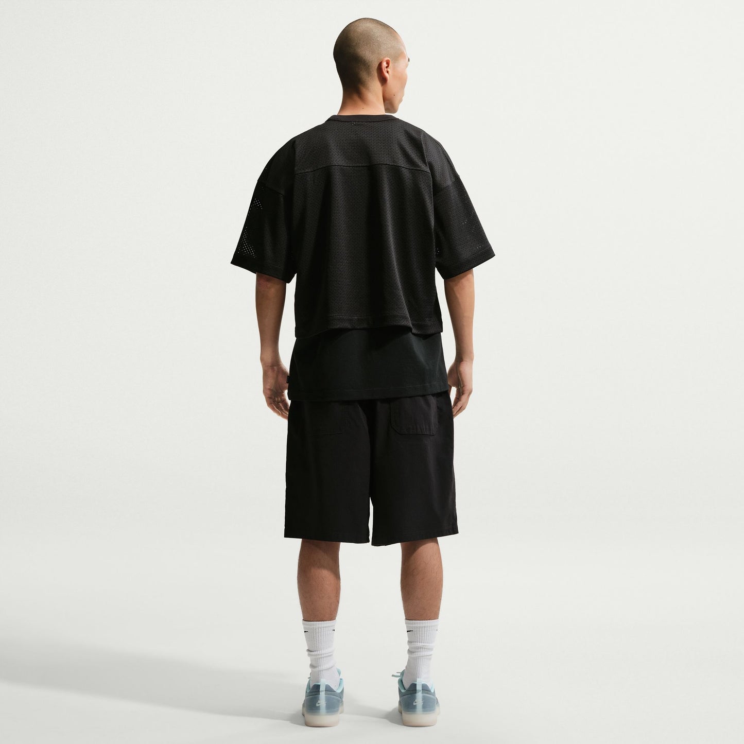 Person wearing a black t-shirt and shorts outfit on a white background