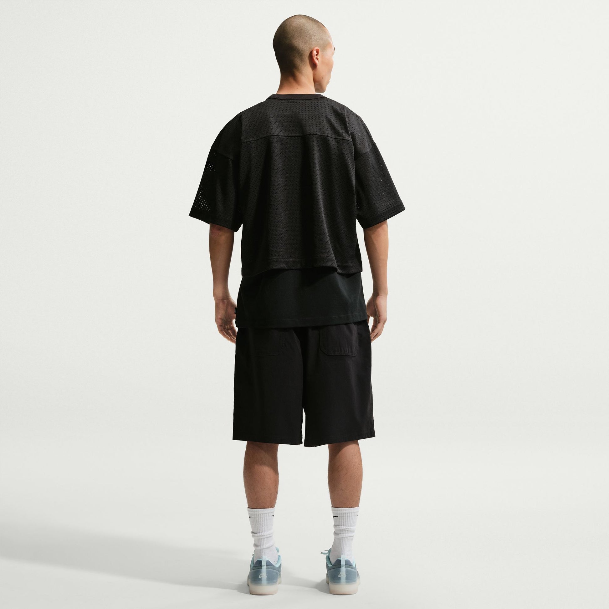 Person wearing a black t-shirt and shorts outfit on a white background