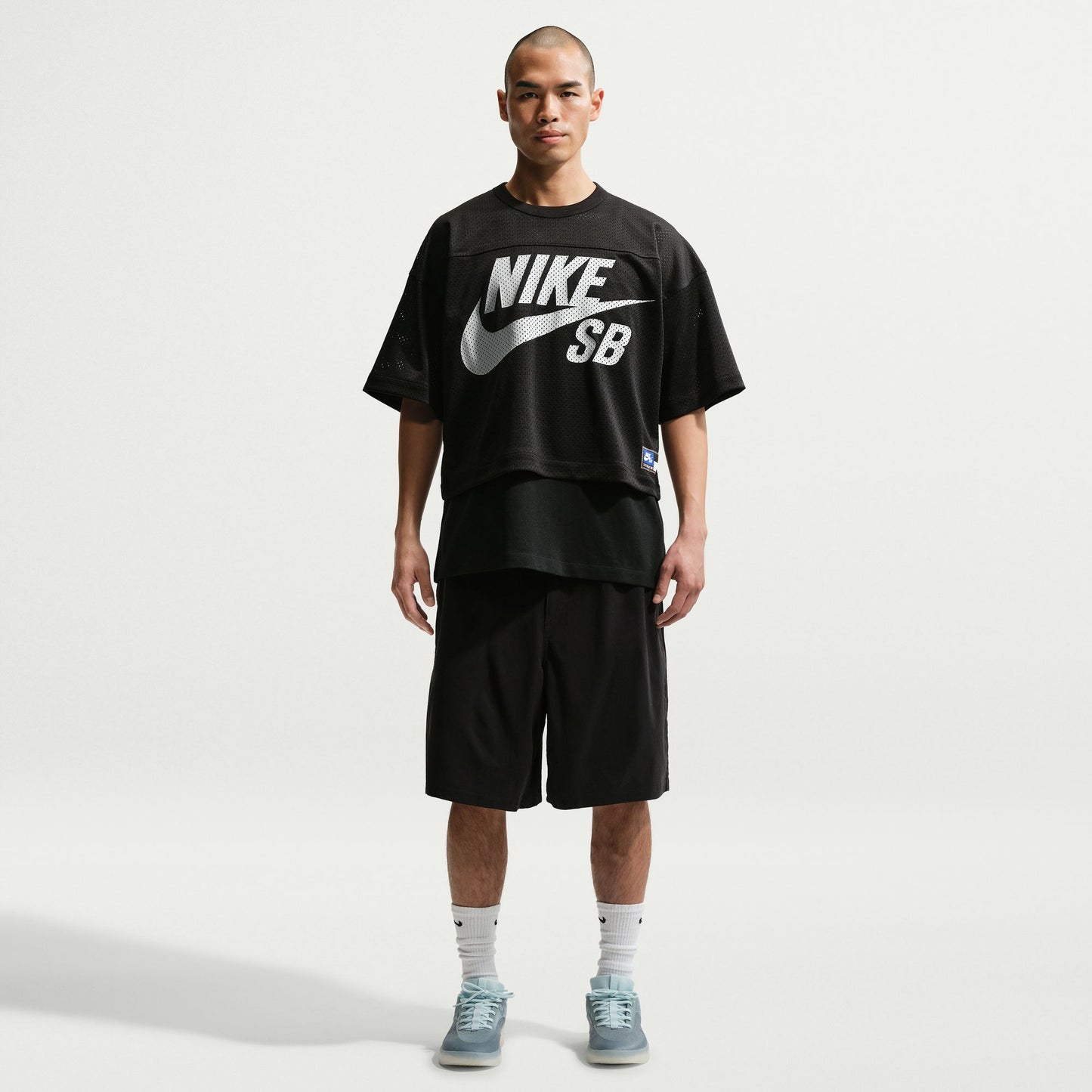 Person wearing a black Nike SB t-shirt and shorts on a white background