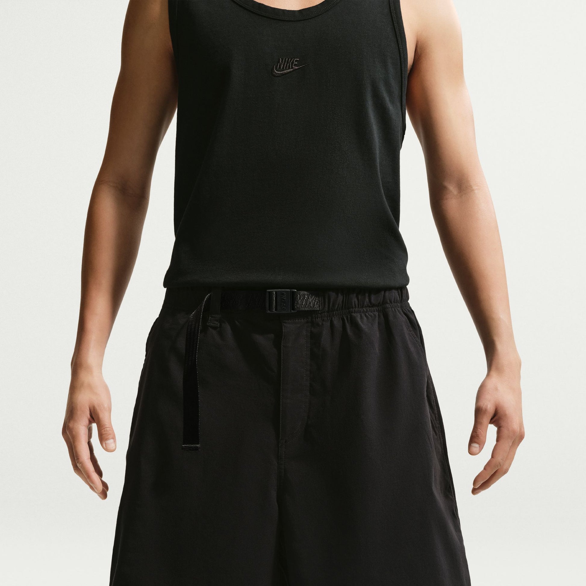 Person wearing a black Nike tank top and black pants on a white background