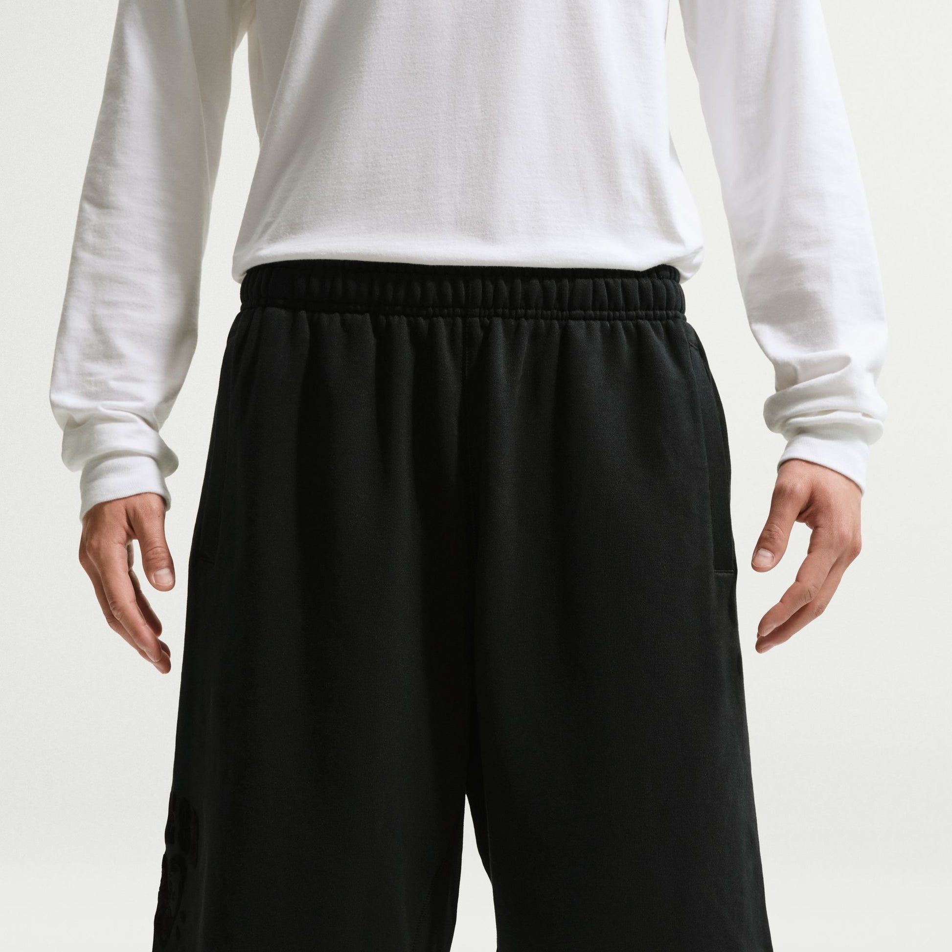 Person wearing black shorts and a white long-sleeve shirt on a white background