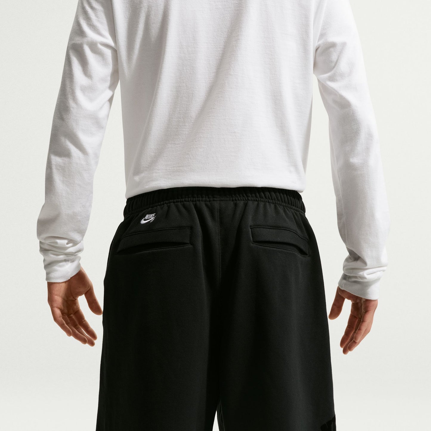Person wearing a white long-sleeve shirt and black shorts on a white background