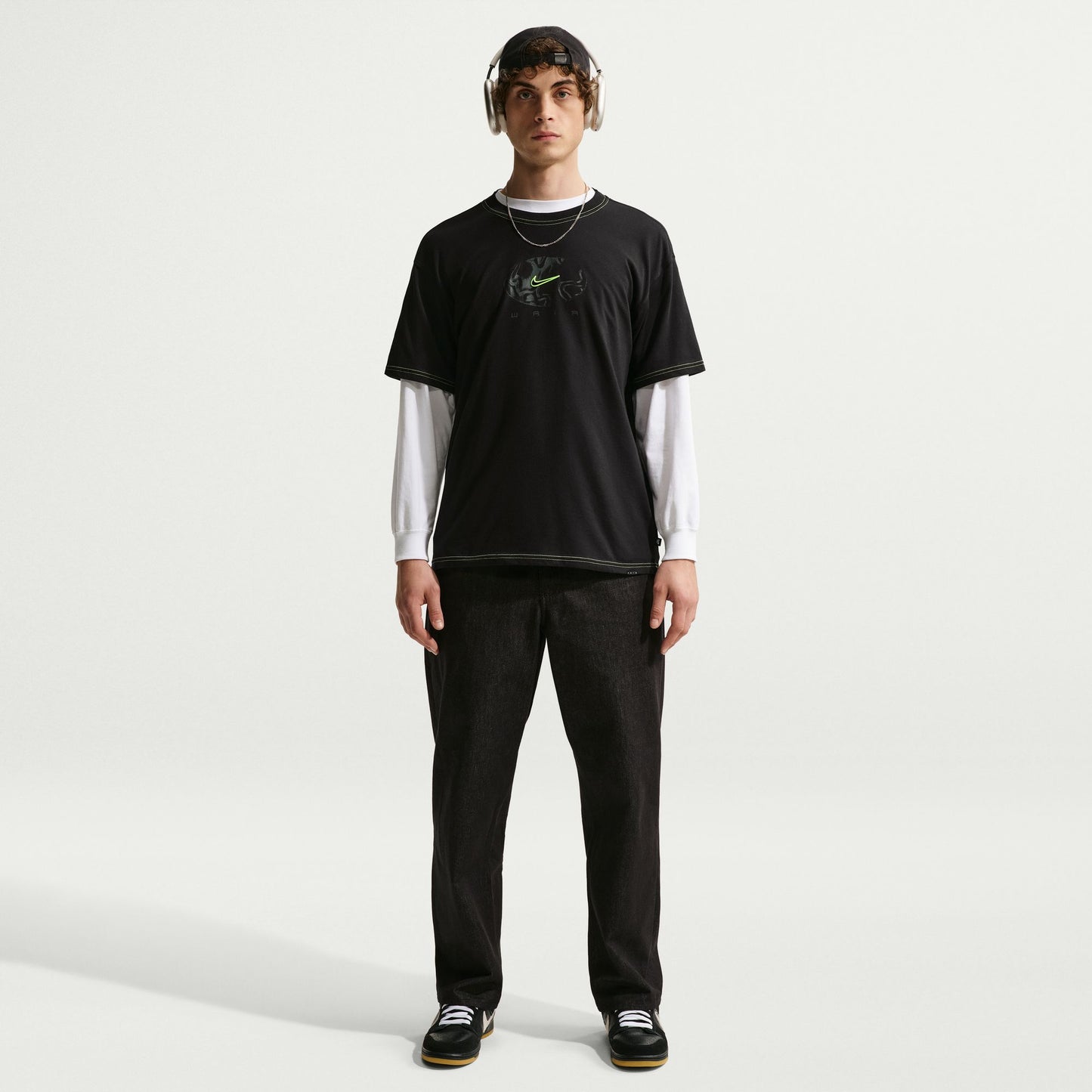 Person wearing a black t-shirt with a logo and dark pants on a white background