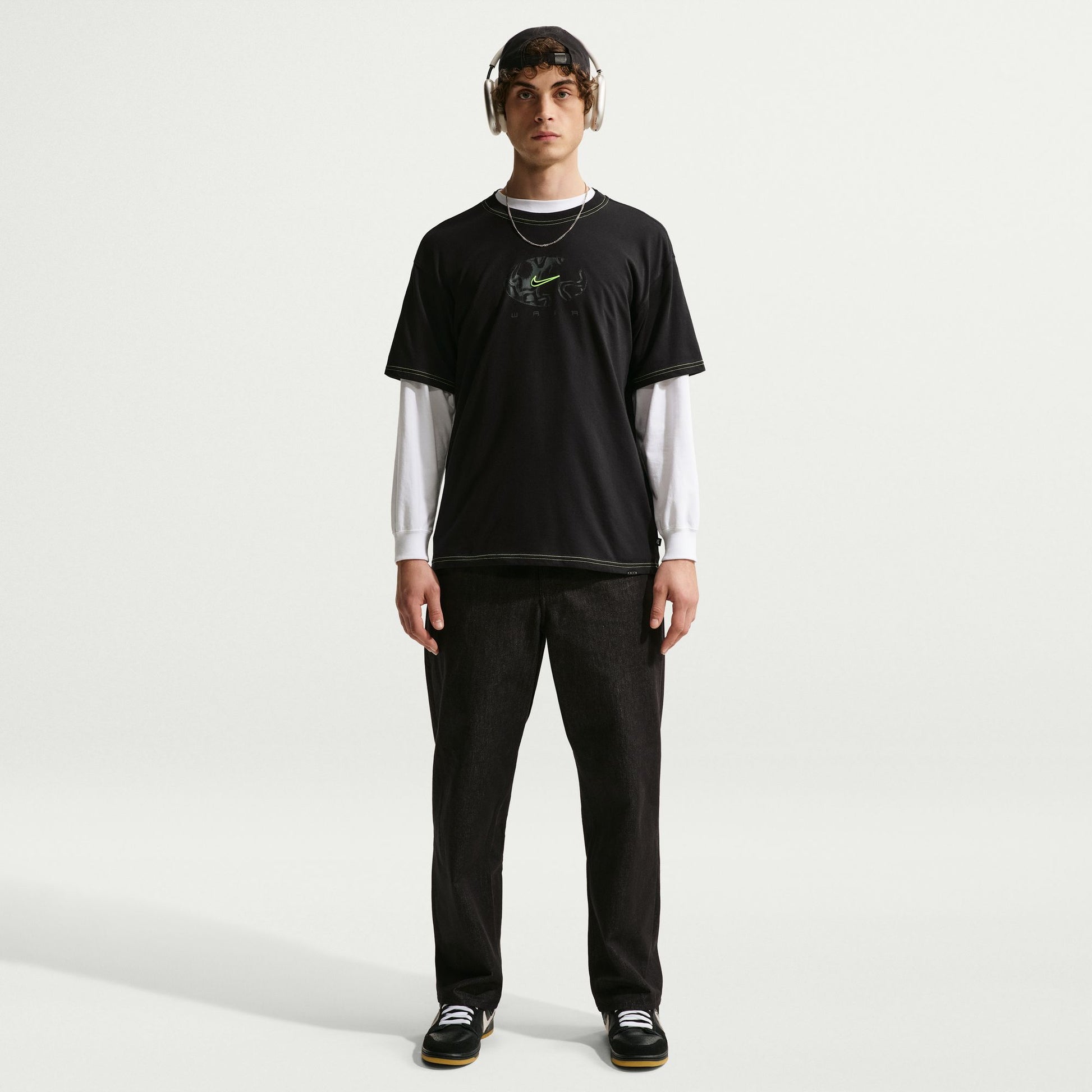 Person wearing a black t-shirt with a logo and dark pants on a white background