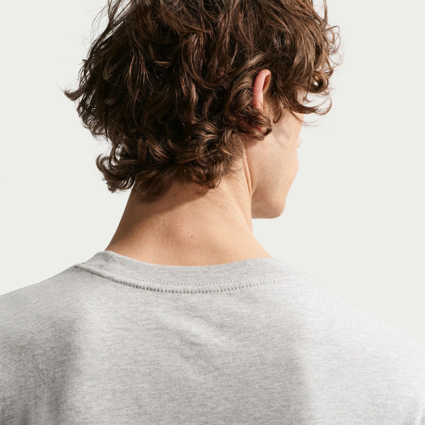 Person wearing a gray shirt with a neutral background