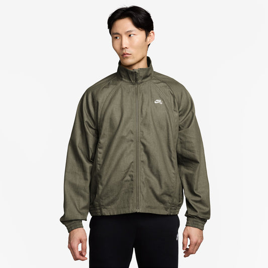 Person wearing a green jacket with a brand logo on a white background