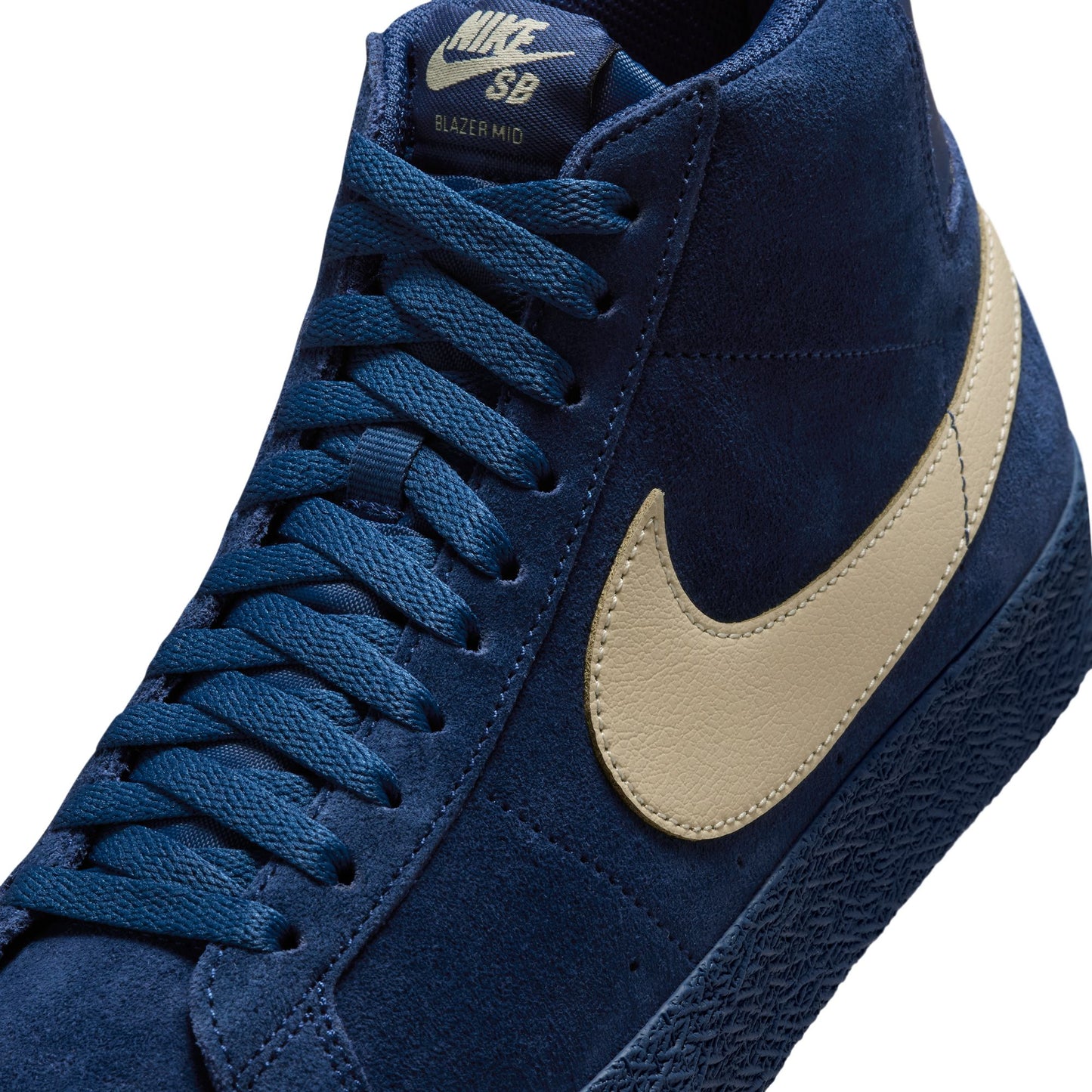 Blue Nike SB sneaker with beige swoosh logo on a white background