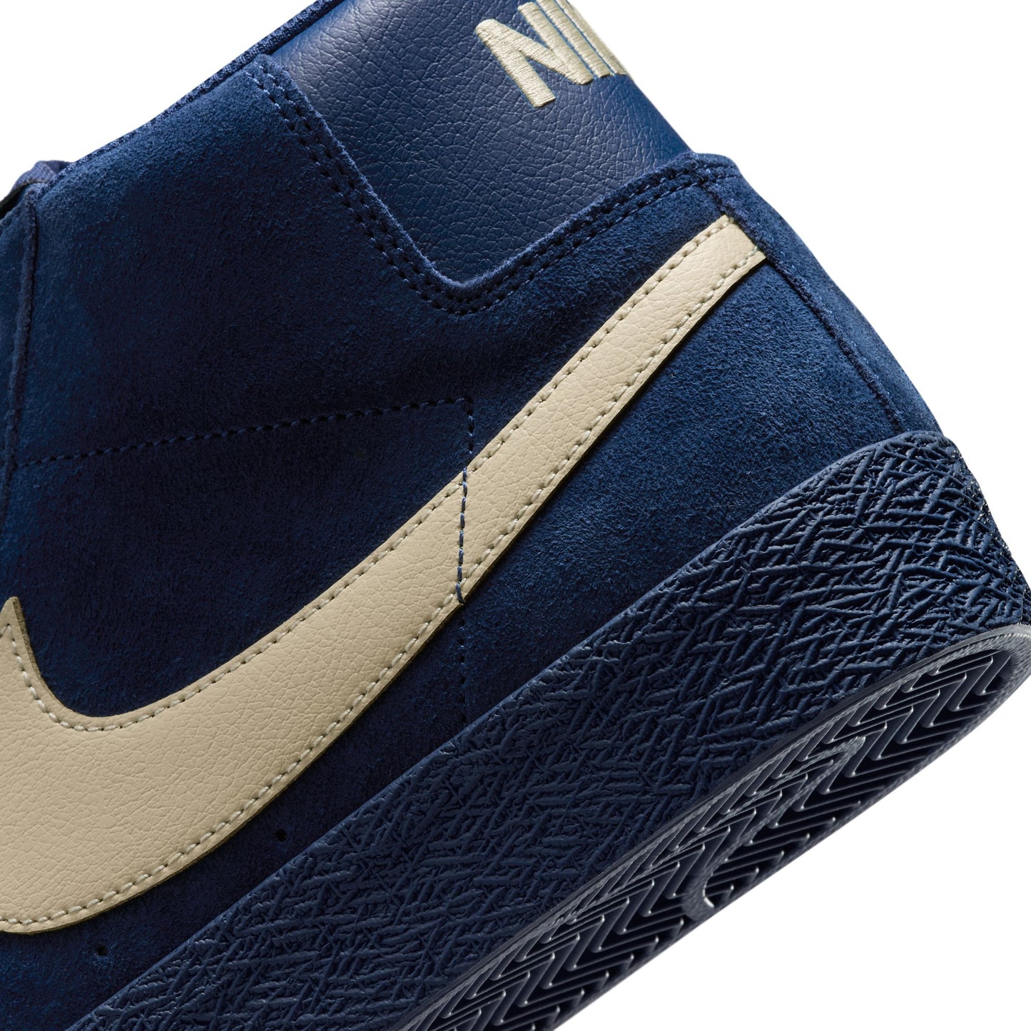 Navy blue sneaker with beige swoosh logo on a white background