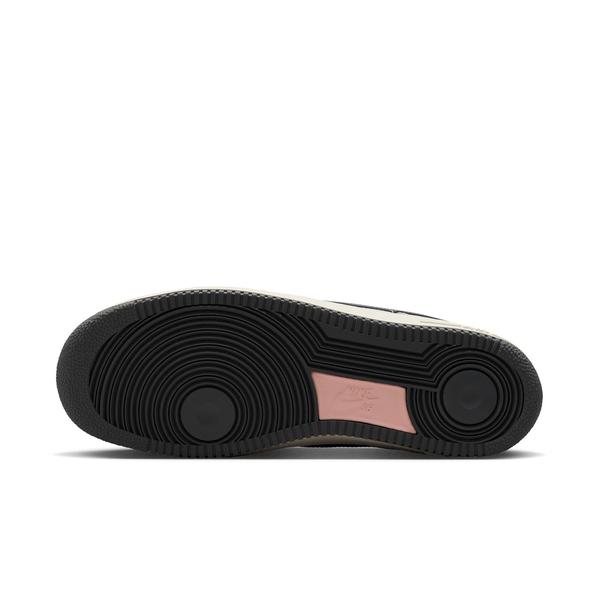A top-down view of a sneaker's black outsole, showing the circular tread pattern and a small pink heel accent on a white background.