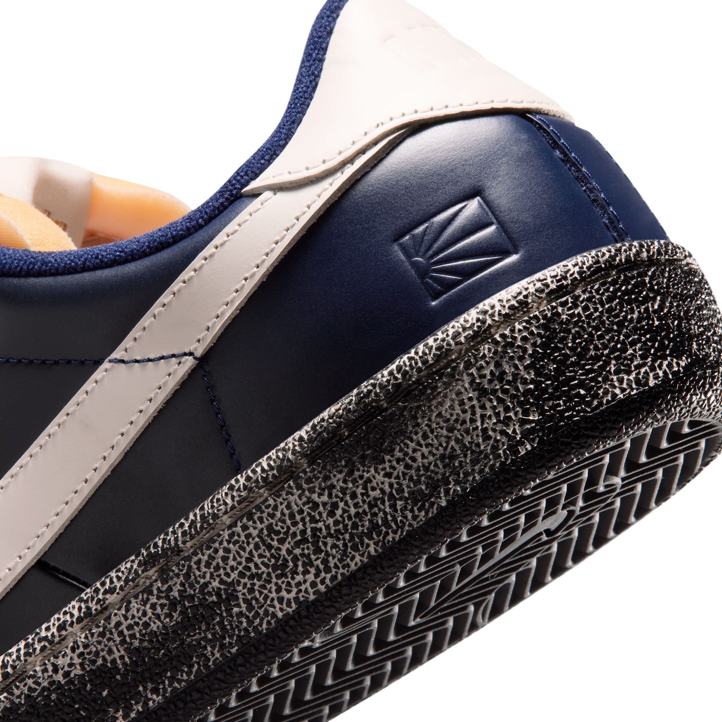 Close-up of a blue and beige sneaker with a brand logo on the heel