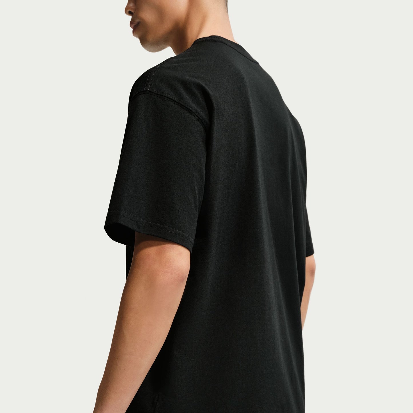 side view of Person wearing a black t-shirt on a plain background