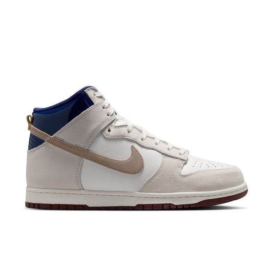 A Nike high-top sneaker in off-white and beige suede with a tan Swoosh, a dark blue collar lining, and a dark brown gum outsole, shown from the side on a white background.