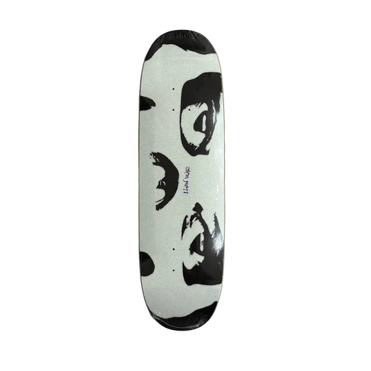 A skateboard deck with a black and white graphic print of a face, wrapped in protective plastic, lying on a white surface.