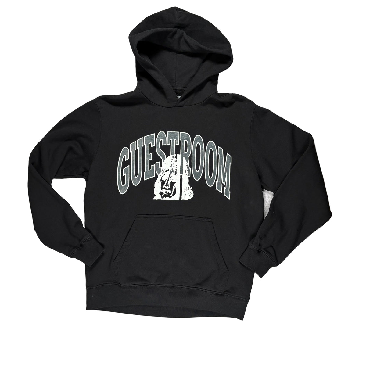 A black pullover hoodie laid flat on a white surface, The hoodie features a large graphic on the chest with the word 'GUESTROOM' in arched gray letters and a white illustrated face in the center.