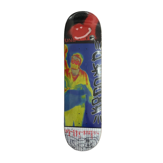 A skateboard deck with a vibrant, colorful graphic print featuring a stylized figure in yellow and blue against a dark background, displayed vertically on a white surface.