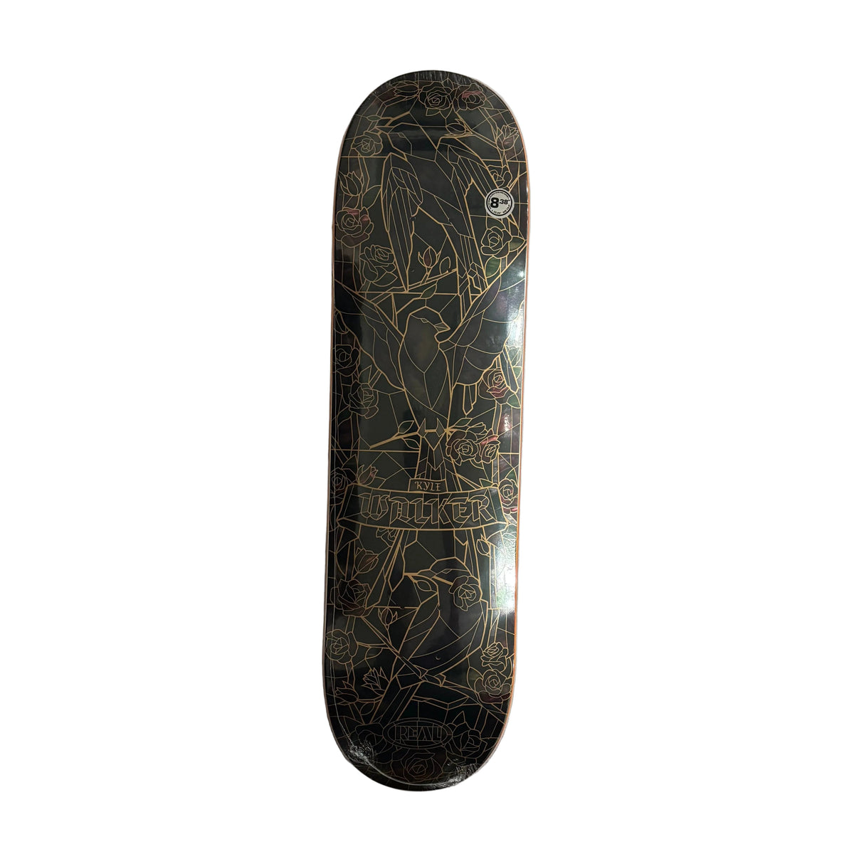 A skateboard deck with a black background and gold line-art illustration, photographed from above on a white background