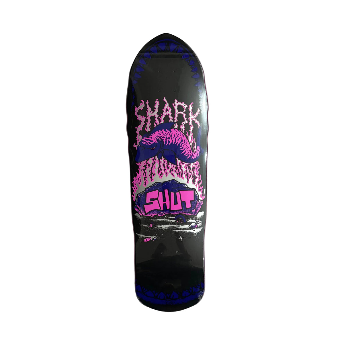 A skateboard deck with a black base featuring a pink and purple shark mouth graphic and the words 'SHARK' and 'SHUT' in stylized lettering, photographed from above on a white background