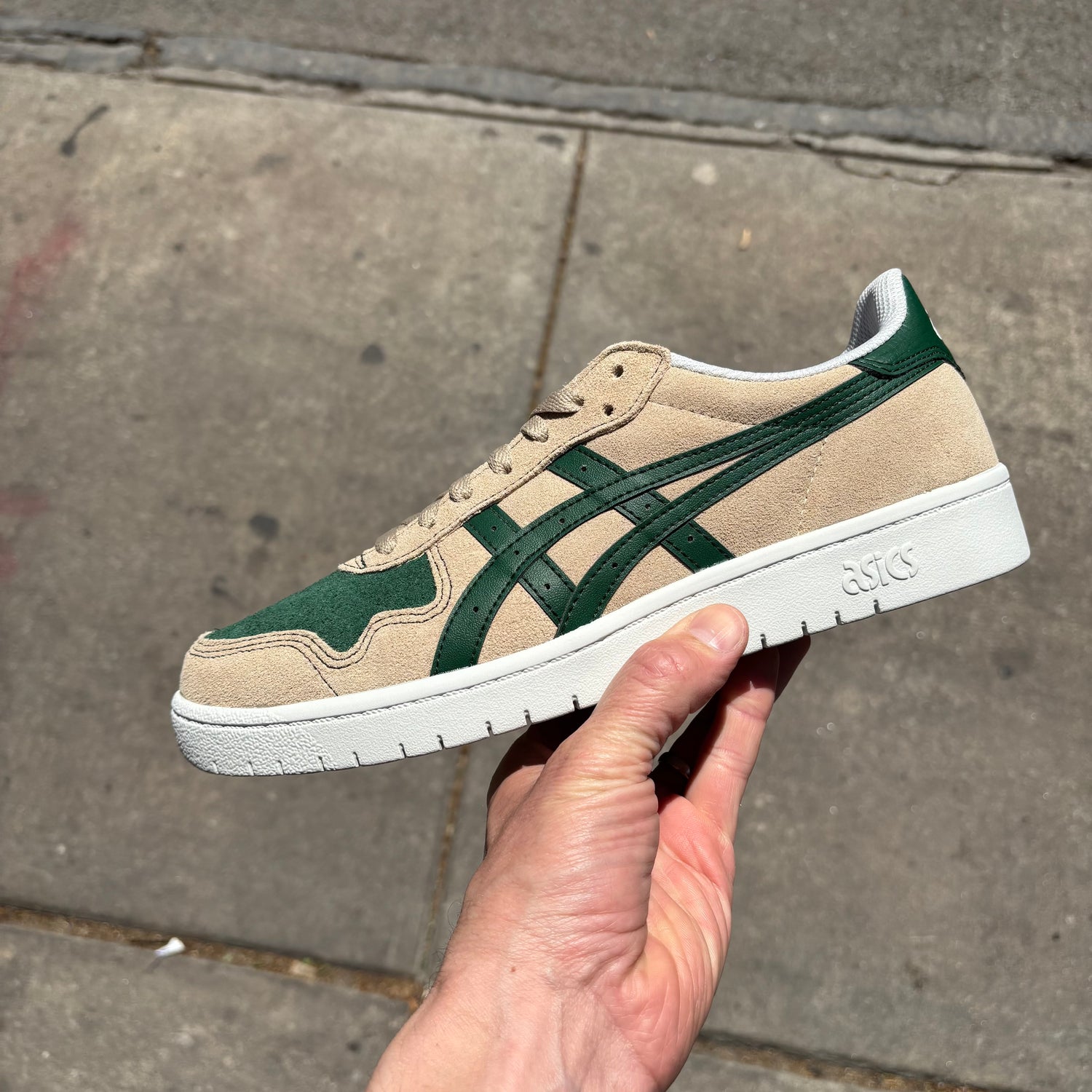 side view of cream colored suede skateboard shoe with green accents and white sole