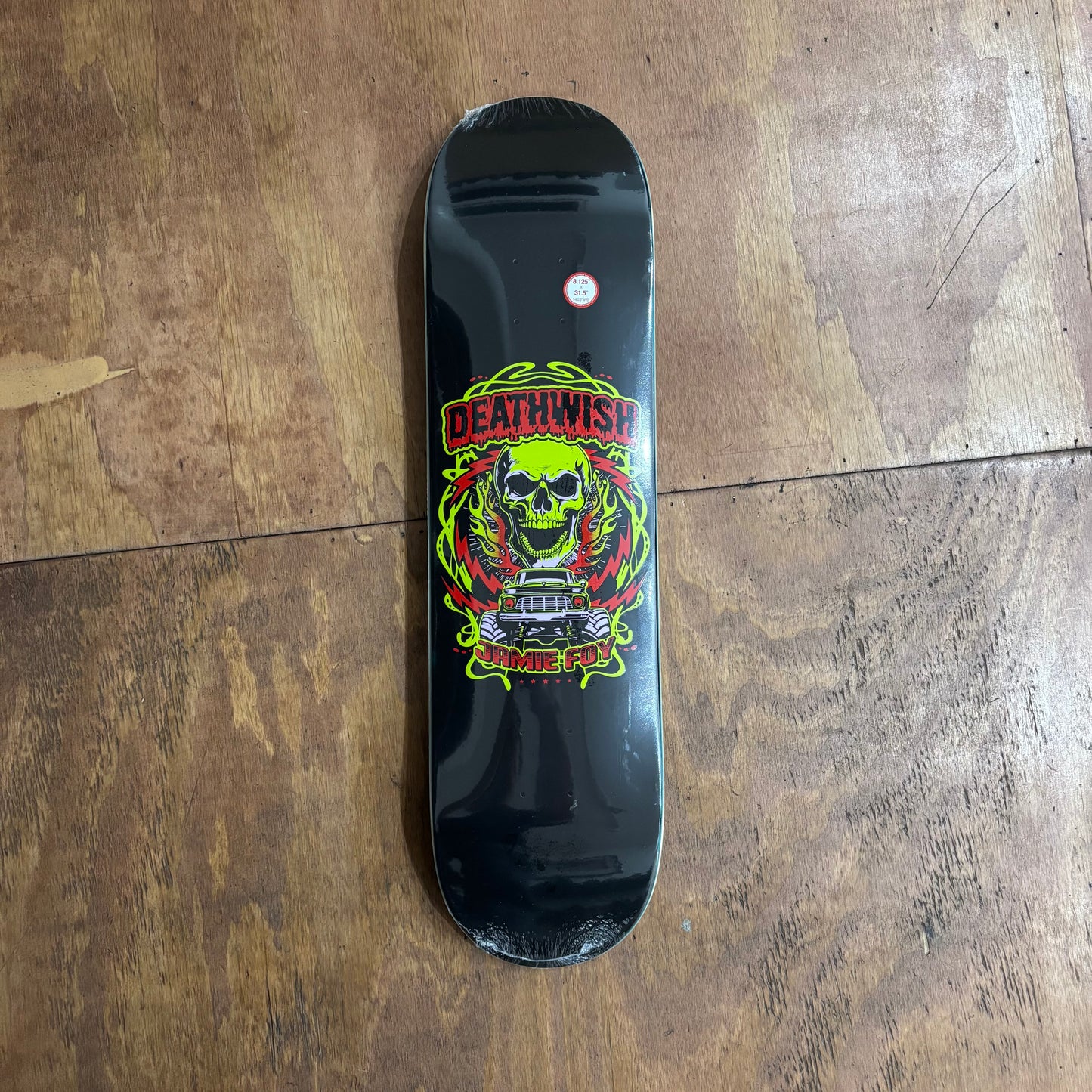 flourescent skull, and monster truck on center of black skateboard deck