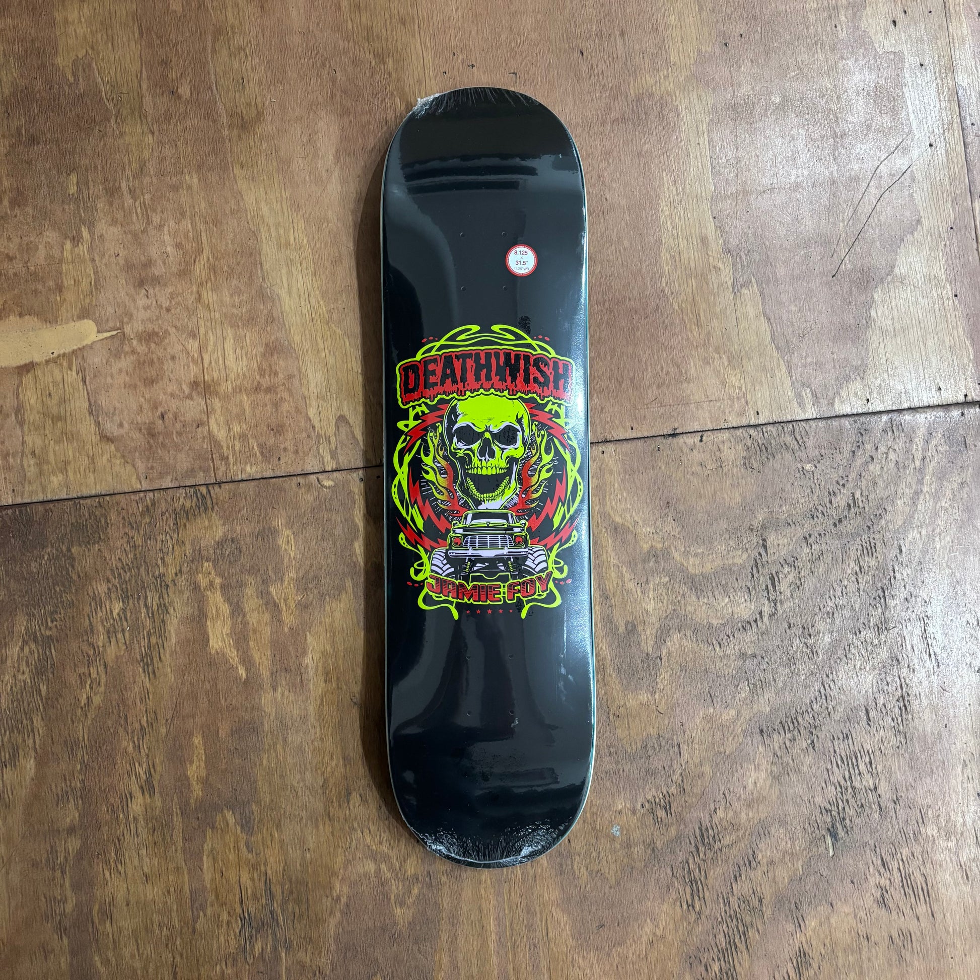 flourescent skull, and monster truck on center of black skateboard deck