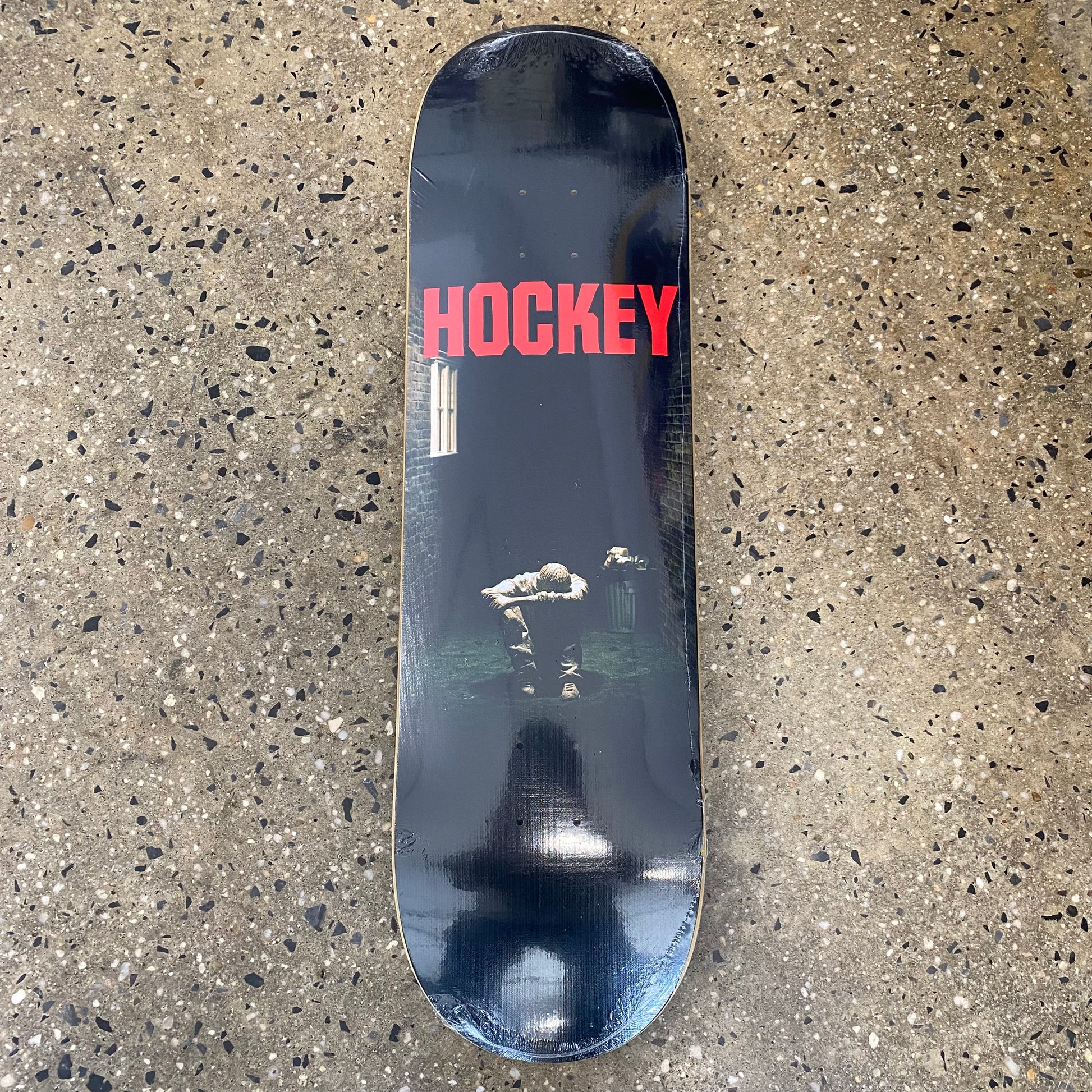 black deck with hockey in red text featuring an image of a man sitting on the ground in the dark