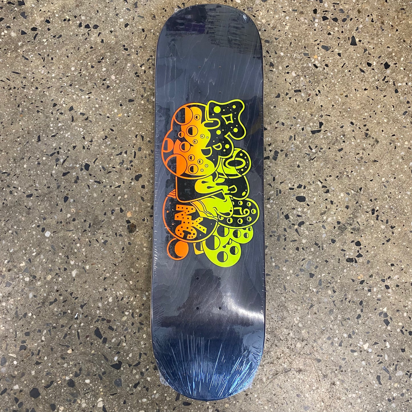 black skateboard deck with yellow and orange graffiti graphic