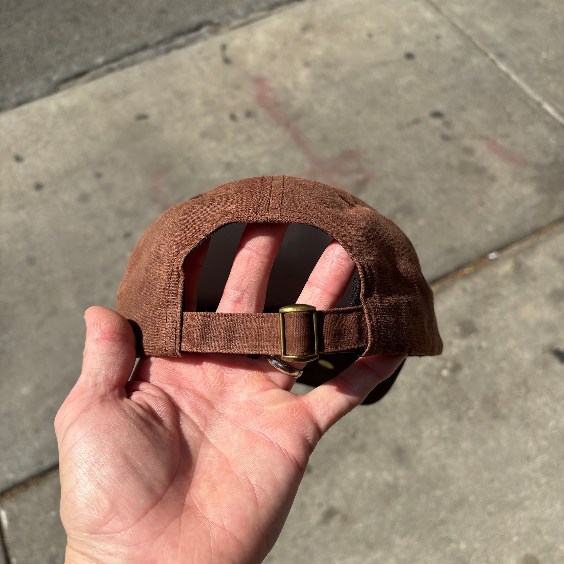 view of closure of brown waxed canvas cap