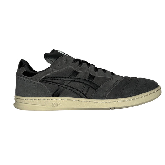 A single dark gray suede sneaker with black accents and a cream-colored sole, photographed from a side angle on a white surface.