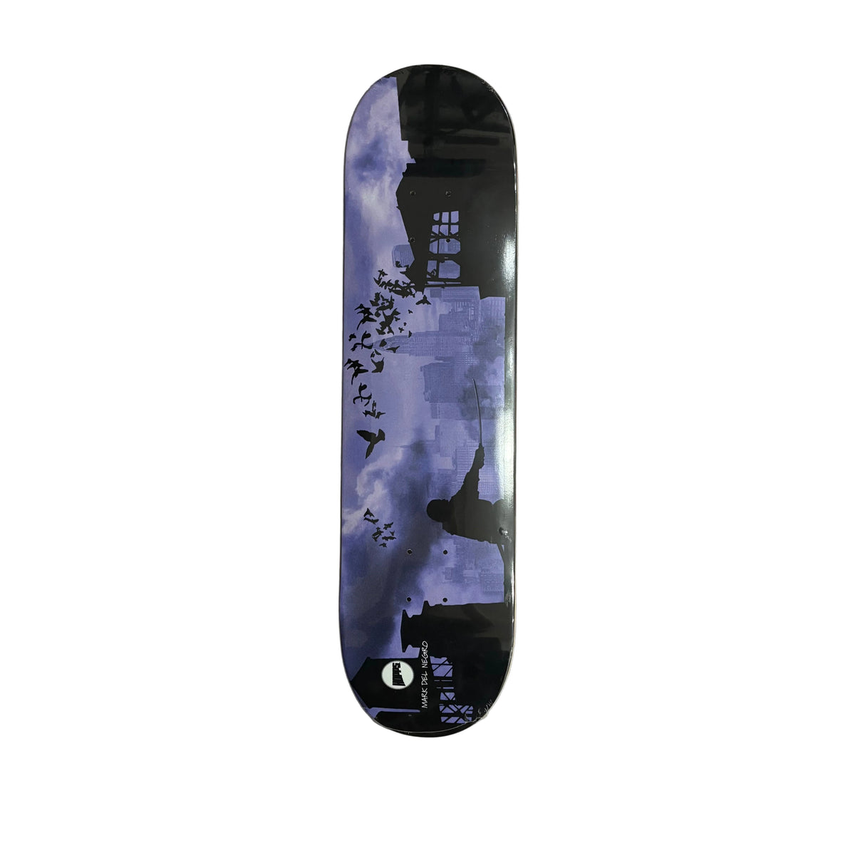 A skateboard deck with a dark graphic print of a city skyline, birds, and a silhouette against a purple-blue sky, photographed from above on a white surface.