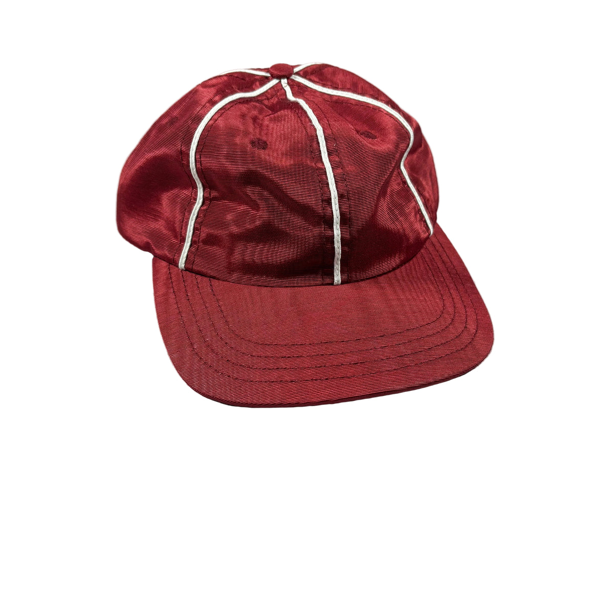 A red baseball cap with white contrast stitching, resting on a white surface.