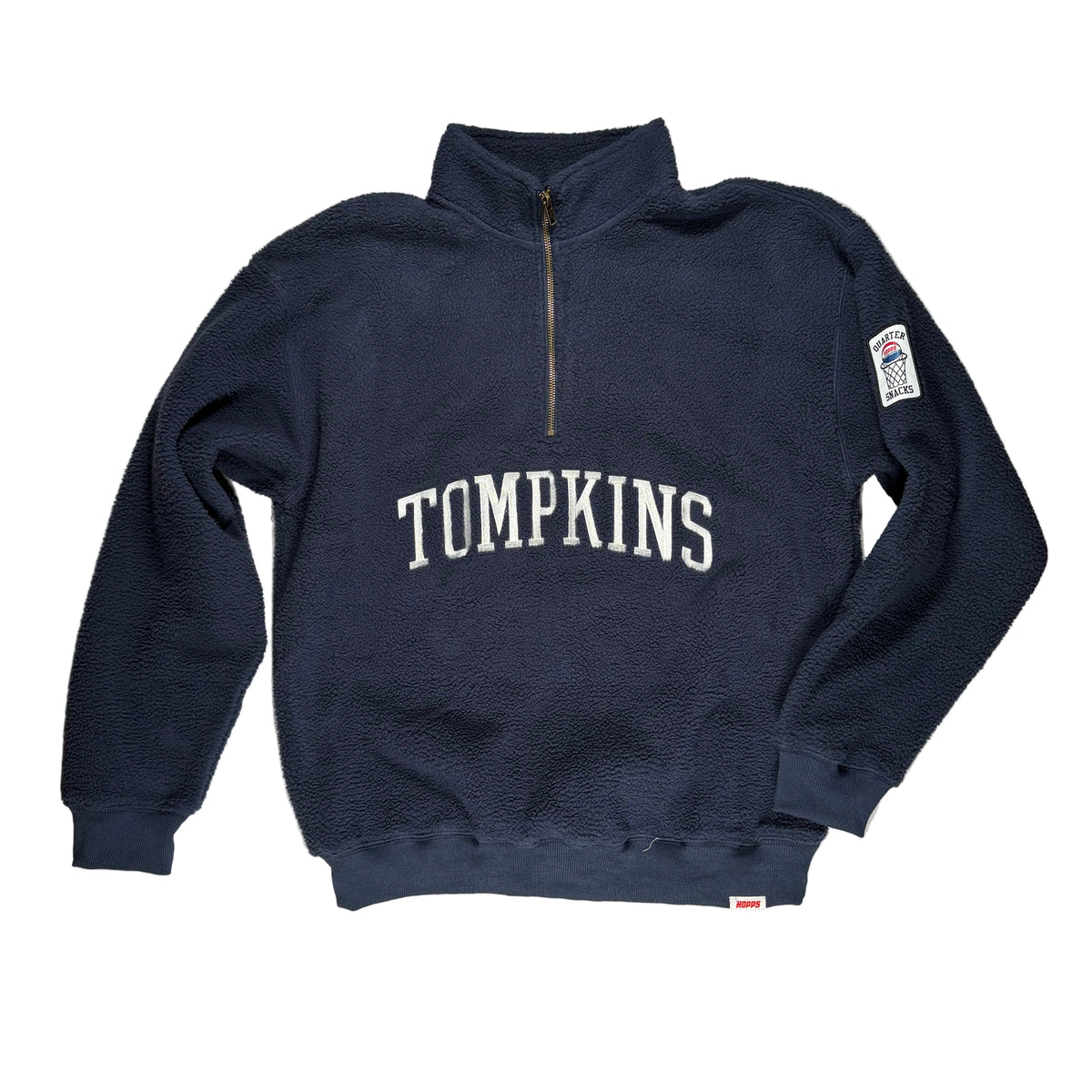 A navy blue fleece quarter-zip sweatshirt with 'TOMPKINS' embroidered in white across the chest, laid flat on a white surface.