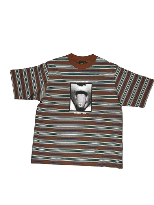 A short-sleeve striped t-shirt with brown, black, and teal horizontal stripes, featuring a central graphic print of a mouth with a tongue sticking out. The shirt is laid flat on a white surface.