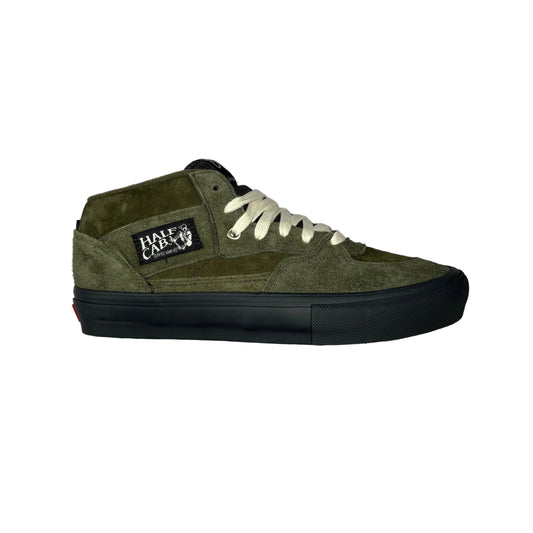 An olive green suede and canvas mid-top skate shoe with off-white laces and a black rubber sole, shown from a side profile on a white background. A 'Half Cab' brand patch is visible on the side.