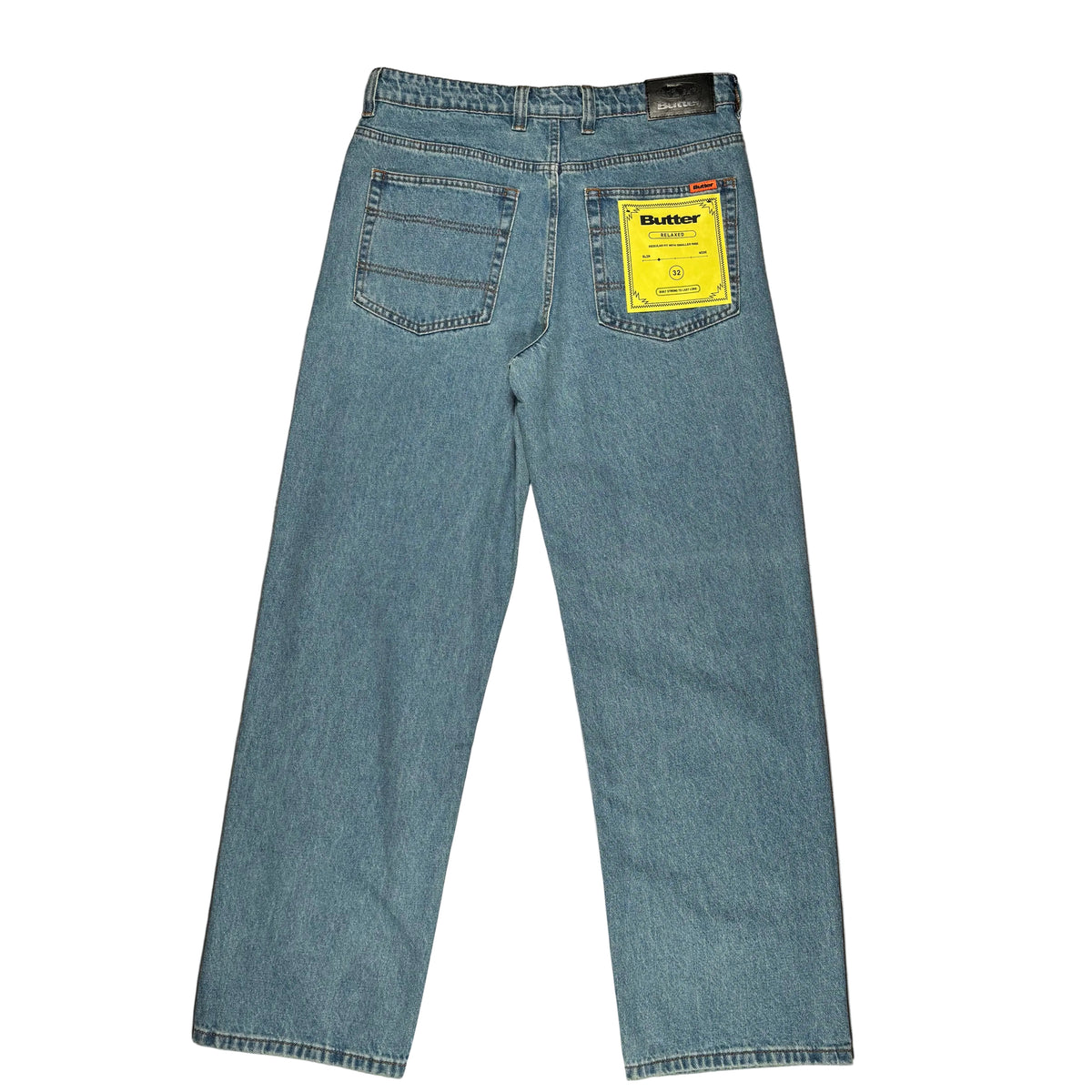 A pair of light blue denim jeans shown from the back, laid flat on a white surface. A yellow Butter brand tag is visible on the back pocket.