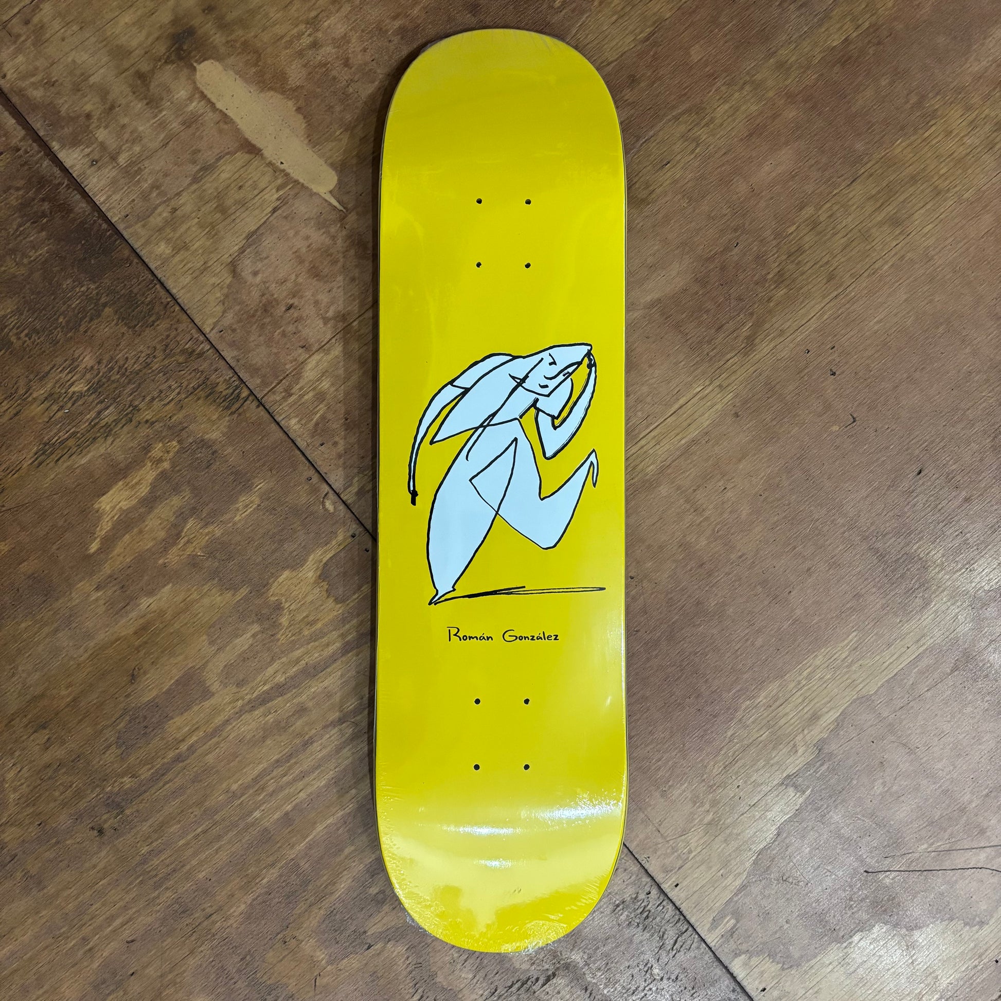 yellow skateboard deck with hand drawn tasteful character doing a small bow