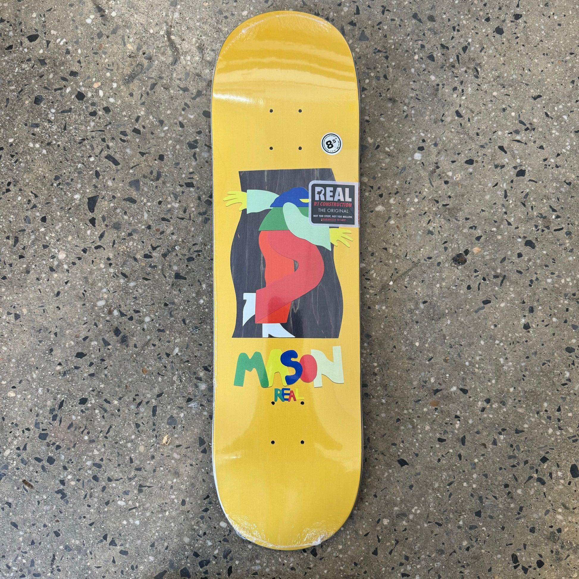 yellow skateboard deck with multicolored art and text in the center