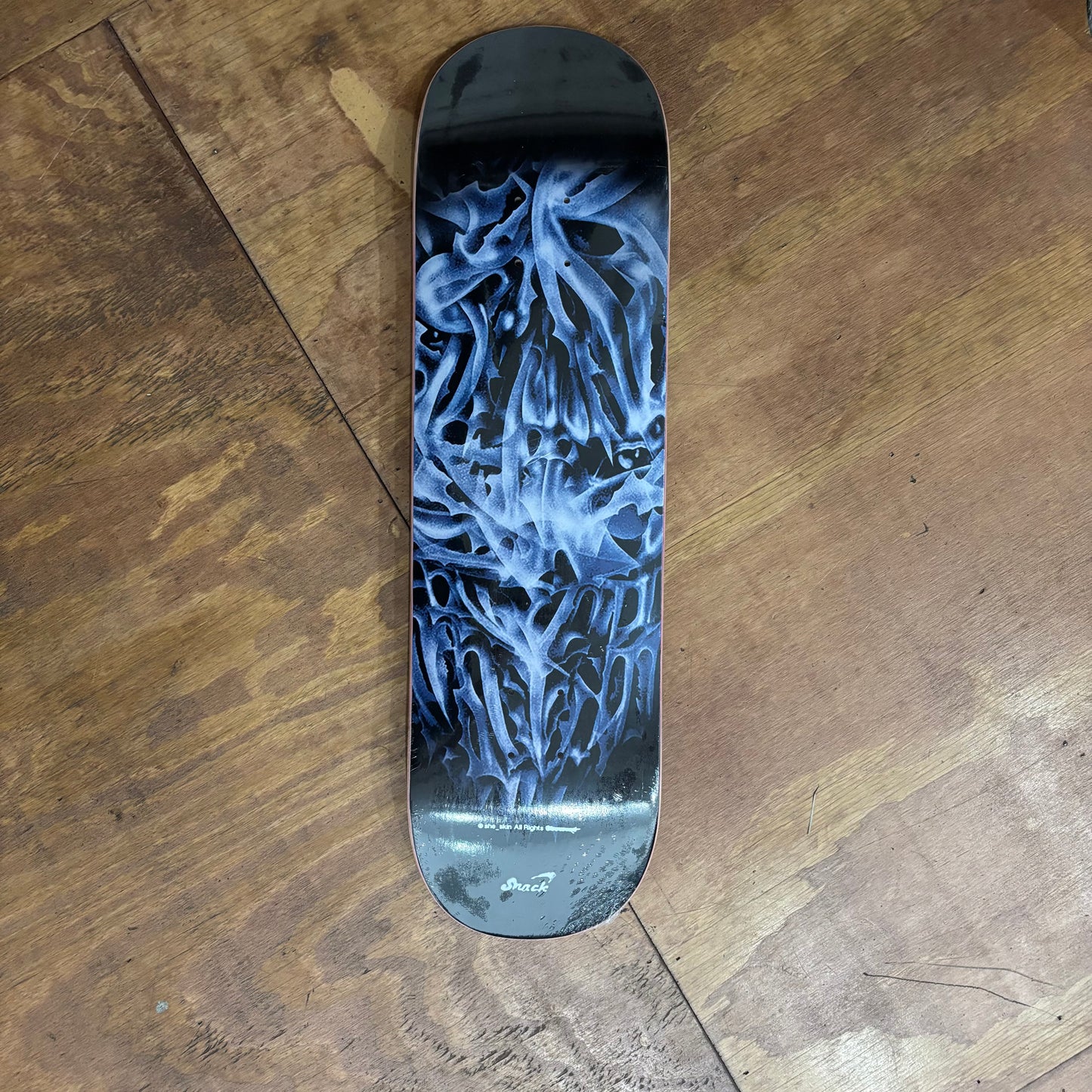 view of chrome lookng face on center of black skateboard deck